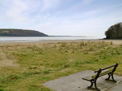 a bench sitting on the side of a beach at Woodlands in Laugharne