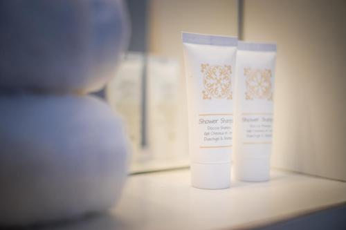 two white bottles of sunscreen sitting on a shelf at Hotel Centrale in Lignano Sabbiadoro