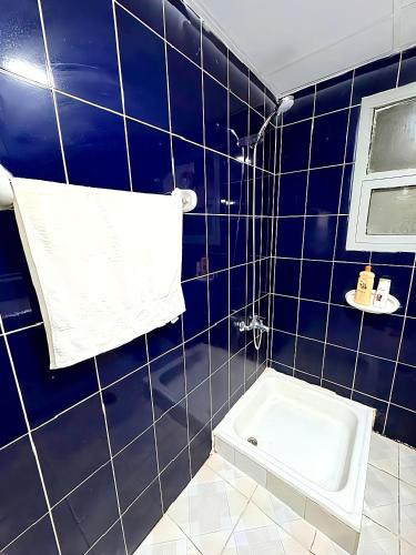 a blue tiled bathroom with a toilet and a towel at Ajman Allegera Elegant Apartment Downtown in Ajman 