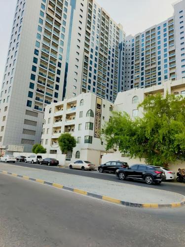 a street with cars parked in front of tall buildings at Ajman Allegera Elegant Apartment Downtown in Ajman 