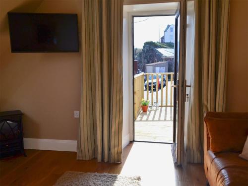 a living room with a couch and a sliding glass door at Rock Cottage in Saint Abbs