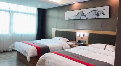 a bedroom with two beds and a tv on the wall at Jun Hotel Guangdong Zhanjiang Xiashan South Railway Station in Zhanjiang