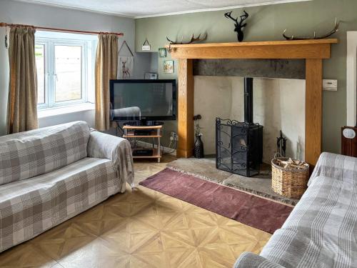 a living room with a couch and a fireplace at Honey Cottage in Auchnarrow