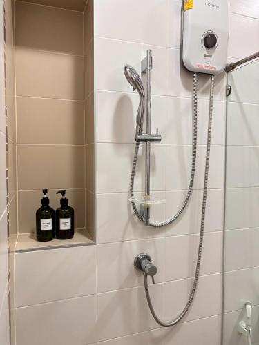 a shower in a bathroom with two bottles of soap at Elegant Getaway House in Hatyai in Ban Thung Ri