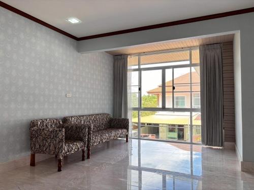 a living room with two chairs and a large window at Elegant Getaway House in Hatyai in Ban Thung Ri