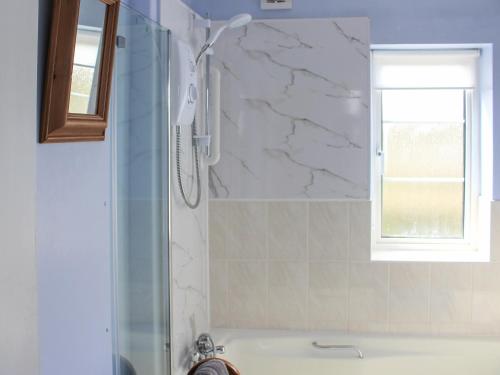 a bathroom with a tub and a shower with a window at The Willows in Chardstock