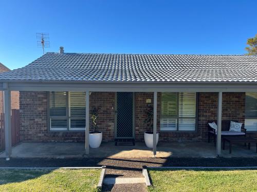 a brick house with a porch with a roof at Mollymook Fantastic Holiday House in Mollymook