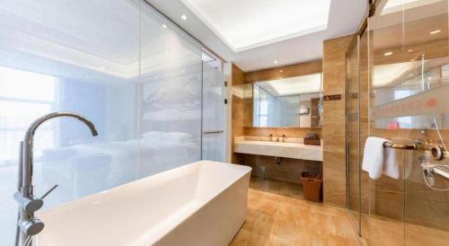 a bathroom with a tub and a shower and a sink at Venus Royal Hotel Nanning East High-Speed Railway Station in Nanning
