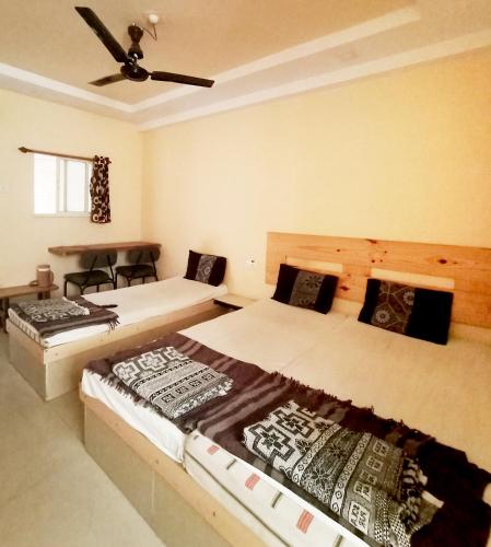 a bedroom with two beds and a ceiling fan at VRP Guest House in Bhuj