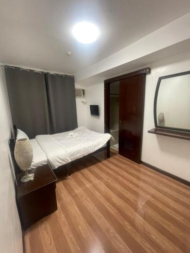 a small bedroom with a bed and a mirror at A venue Residences 1801 in Manila