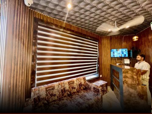 a man standing in front of a window with a couch at hotel k stay by Anmol in Haridwār