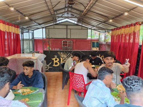 a group of people sitting at tables eating food at Bhaskar homestay varkala in Varkala