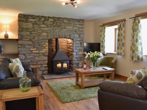 a living room with a stone fireplace and a couch at Gorsddu in Llanwrthwl