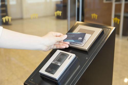 a person holding a cell phone in a cash register at Sanco Inn Kuwana Ekimae in Kuwana