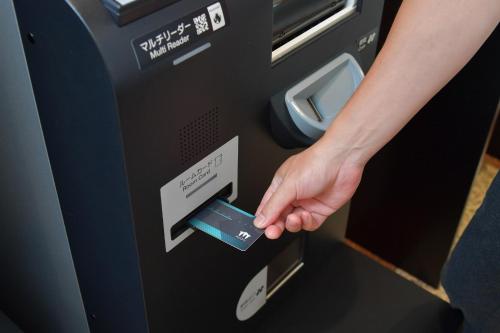 a hand inserting a credit card into a atm machine at Sanco Inn Kuwana Ekimae in Kuwana