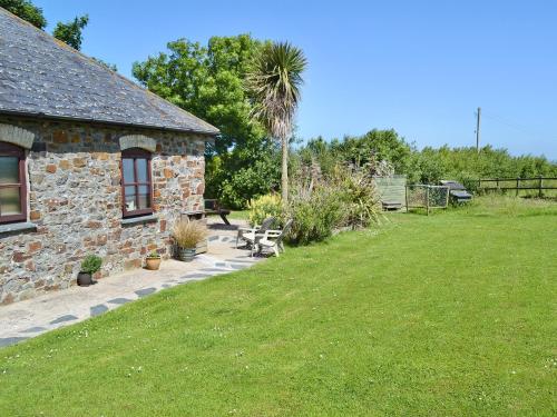 a stone building with a grassy yard next to a house at Goose Cottage - Ukc2676 in Poundstock