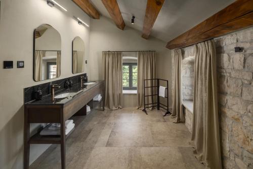 a bathroom with two sinks and a stone wall at San Tomasini Heritage Hotel & Wedding Venue in Višnjan