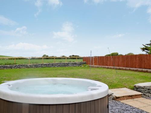 a hot tub in a yard with a fence at Yr Hen Feudy in Valley