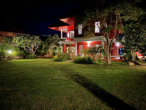 a house with a green yard at night at Baan Plumeria บ้านภูมิเรีย in Phetchaburi