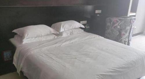 a large white bed with white sheets and pillows at Grand Nest Hotel (Tang Jia Wan Beach) in Zhuhai