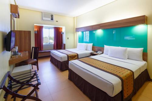 a hotel room with two beds and a desk at Microtel by Wyndham General Santos in General Santos