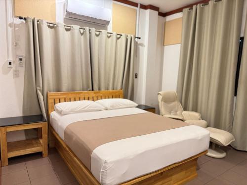 a bedroom with a bed and a chair at Buakao Inn in Thongsala