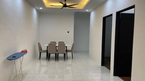 a dining room with a table and chairs and a ceiling fan at HOMESTAY ADELIa in Kangar
