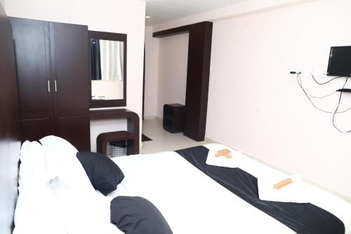a person sitting on a bed in a bedroom at Erica Hotel International in Perintalmanna