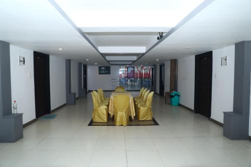 a long hallway with yellow chairs and a table at Erica Hotel International in Perintalmanna