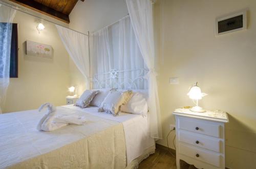 a bedroom with a white bed with a lamp and a dresser at Agriturismo Tenuta Umberto I in Ripacorbaria