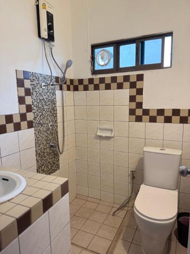 a bathroom with a toilet and a shower and a sink at Buakao Inn in Thongsala