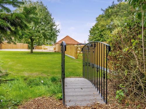 a gate with a wooden walkway in a yard at Woodpecker Barn - Uk38613 in Wisbech