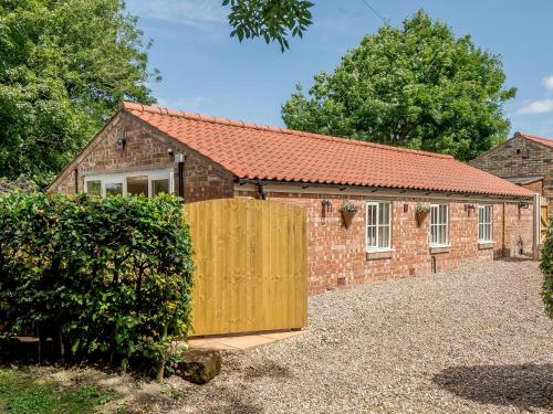 an external view of a brick house with a wooden gate at The Chicken Coop in Fulletby