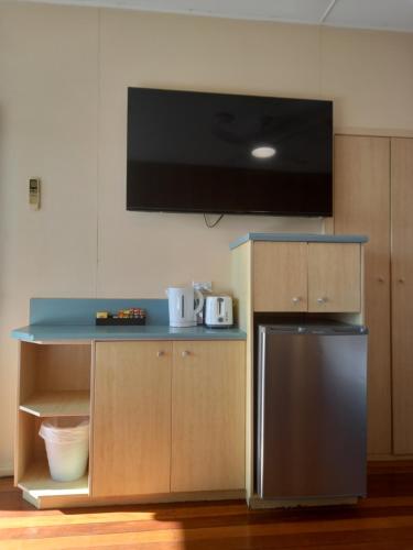 a kitchen with a refrigerator and a tv on the wall at The Original Bel-Air Motel in Port Macquarie