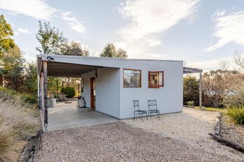 a small white house with two chairs in a driveway at Timber & Stone - Sanctuary Eco Studio in Yapeen