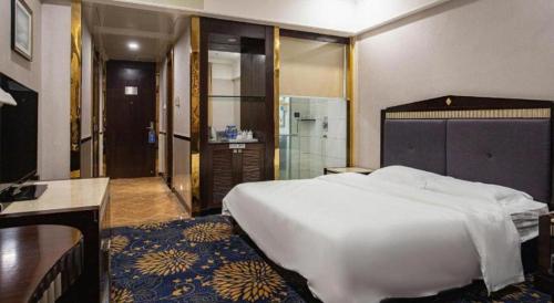 a bedroom with a large white bed and a bathroom at Zhongshan Hui Quan Hotel in Zhongshan