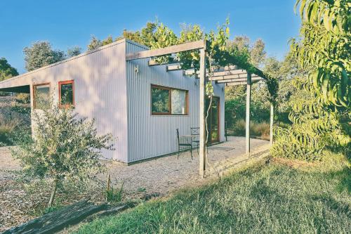 a small house with a pergola in a garden at Timber & Stone - Sanctuary Eco Studio in Yapeen