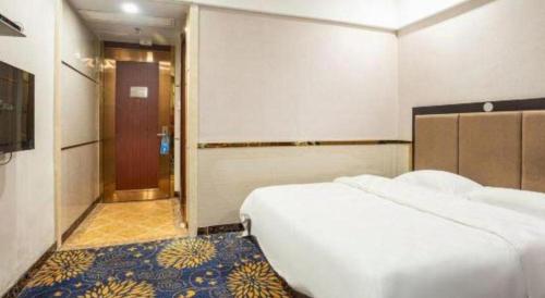 a hotel room with a bed and a hallway with a door at Zhongshan Hui Quan Hotel in Zhongshan