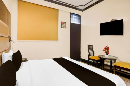 a bedroom with a bed and a table and a tv at Super Townhouse Sushant Lok Phase 1 Formerly Hotel Neven in Gurgaon