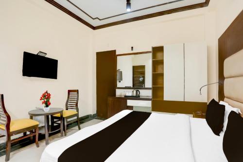 a bedroom with a bed and a table and a kitchen at Super Townhouse Sushant Lok Phase 1 Formerly Hotel Neven in Gurgaon