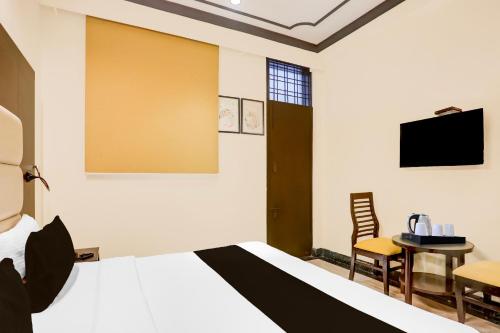 a bedroom with a bed and a table and a tv at Super Townhouse Sushant Lok Phase 1 Formerly Hotel Neven in Gurgaon