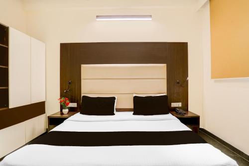 a bedroom with a large white bed with black pillows at Super Townhouse Sushant Lok Phase 1 Formerly Hotel Neven in Gurgaon