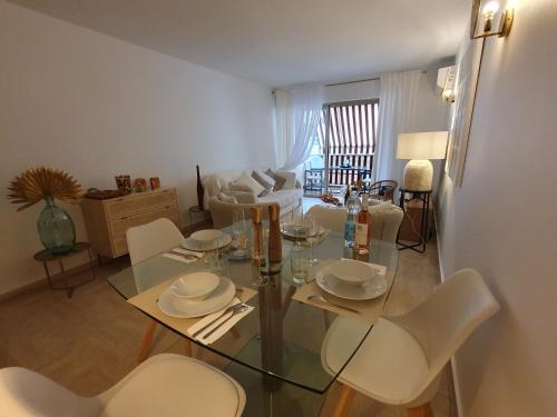 une salle à manger avec une table en verre et des chaises blanches dans l'établissement Appartement 2 pièces carré d or Les Floralies, à Antibes