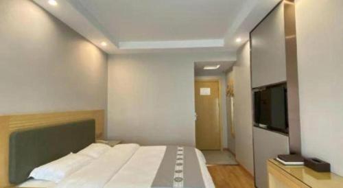 a bedroom with a large bed and a flat screen tv at Shell Hefei Luyang District Sipai Building Subway Station Hotel in Hefei