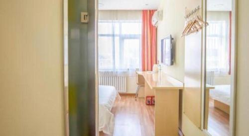 a room with a bedroom with a desk and a bed at 7Days Inn Tianjin Fifth Avenue Youyi Road Branch in Tianjin
