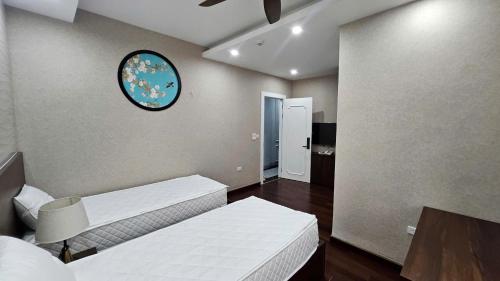 a room with two beds and a clock on the wall at The Dahlia Hotel & Apartments in Hanoi