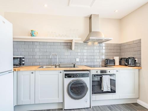 a kitchen with a washing machine and a sink at The Roost-Uk37326 in Cromer