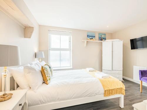 a white bedroom with a white bed and a window at The Roost-Uk37326 in Cromer