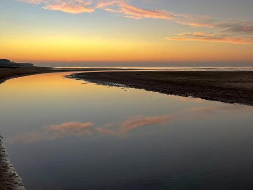 a reflection of the sky in the water at sunset at The Barn in Hunstanton