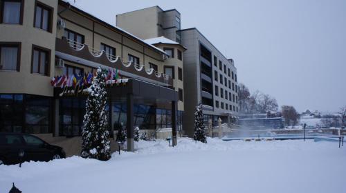 a building with snow on the ground in front of it at Hotel President in Baile Felix